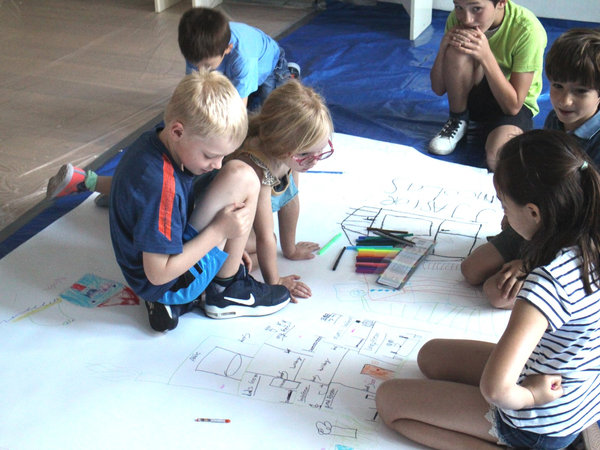 children brainstorming ideas on huge sheet of paper
